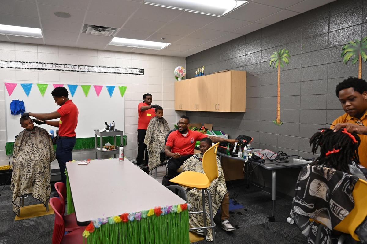 Four barbers, all who work at Harrell’s & Son’s barber shop, work on free haircuts for elementary students on Monday, May 19, 2025, at Union Elementary School in Macon, Georgia. The barbers all volunteer their time to give free haircuts for students through Barbers On Duty, a local non-profit started by Duade Harrell.