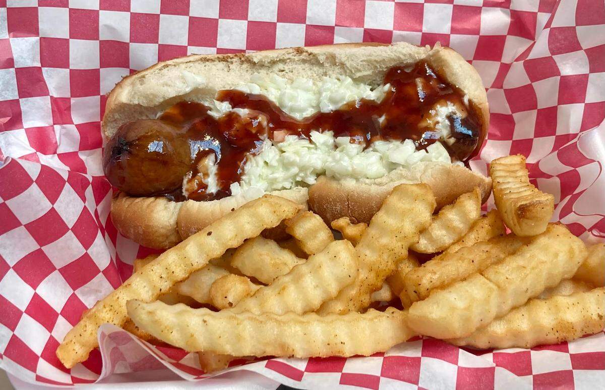 A sausage dog topped with coleslaw (instead of its regular sauerkraut ) and spicy BBQ sauce with a side of fries at The Georgia Dog, a new walk-up restaurant at the Houston County Galleria in Centerville.