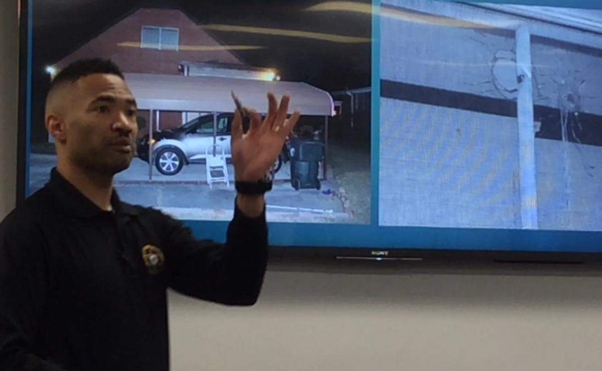 Bibb County sheriff's investigator Marcus Baker holds a round of ammunition like the kind that is thought to have killed Ann Leonard and Marlon Williams. In the background are police photographs of Leonard's window and her back yard.