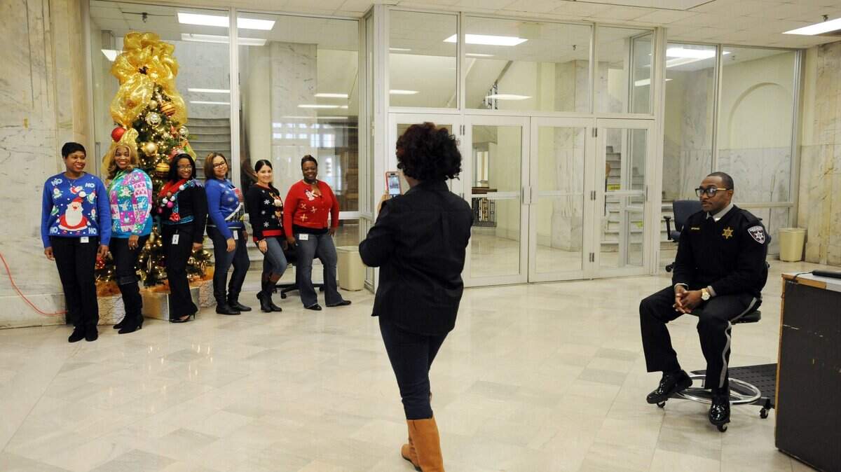Chante Drumgold, center, makes a picture of Clerk of Superior Court Erica Woodford (left) and her staff in the lobby of the Bibb County Courthouse after lunch in this 2016 Telegraph file photo. "This is the clerk team,'' said Woodford.  "It's holiday sweater day or ugly sweater day.  It's a cold dreary day but we're festive inside.''