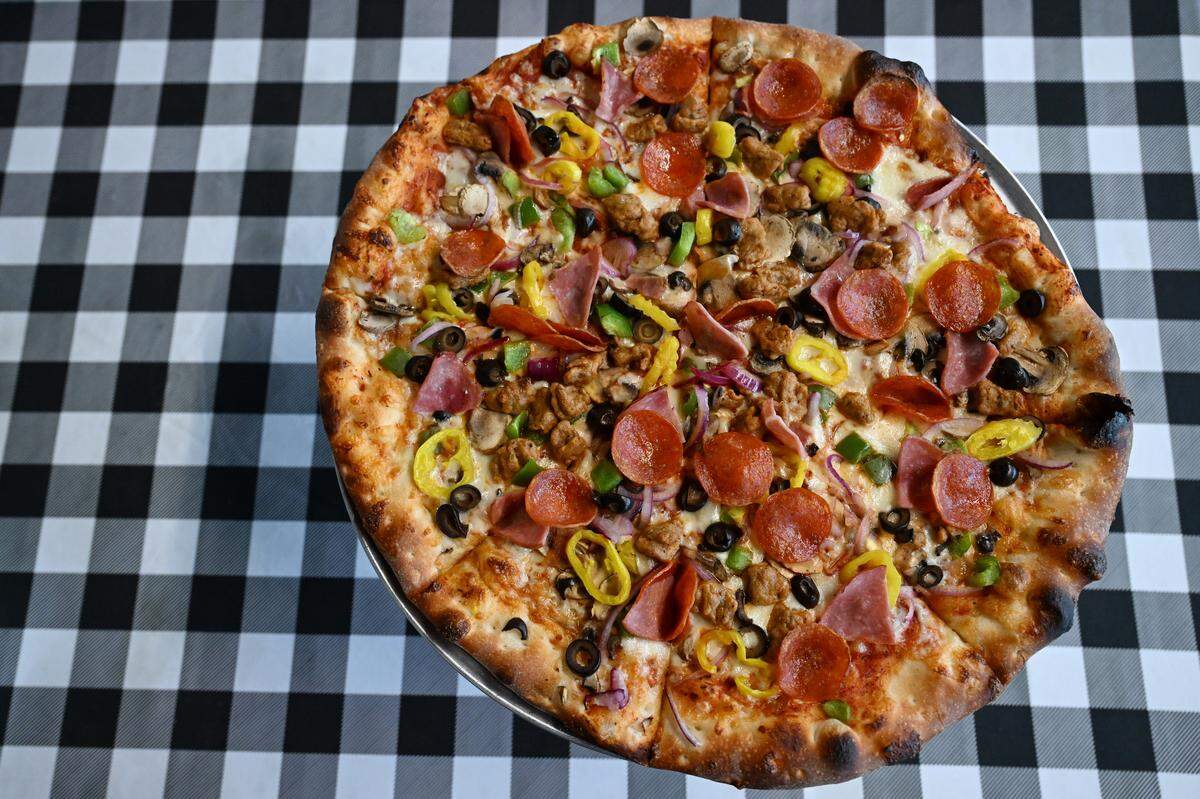 A large “The Home Slice” pizza at Home Slice Pizza on Tuesday, Aug. 26, 2025, in downtown Perry, Georgia. The pizza includes pepperoni, ham, sausage, green peppers, black olives, mushrooms, banana peppers, onions and mozzarella.
