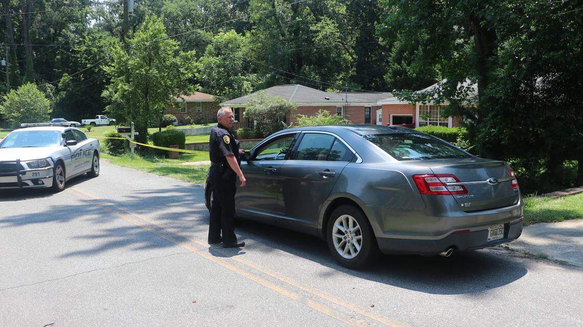 A Warner Robins police officer speaks with someone Sunday in front of a house on Willow Avenue where a woman was stabbed to death.