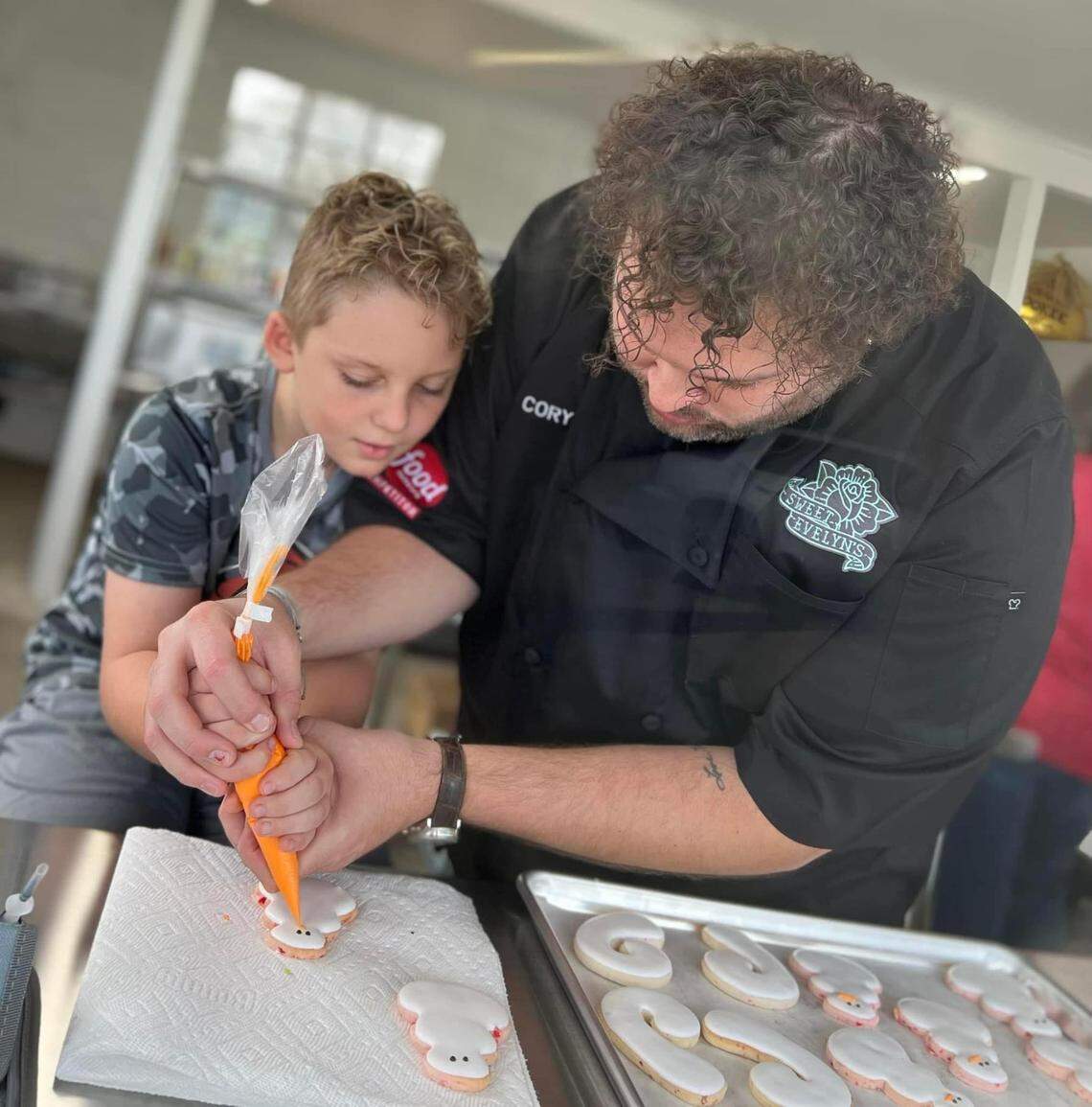 Cory Jones, an industry professional cookie artist and owner of Sweet Evelyn’s, right, decorates cookies with Brannen McIntyre, son of Jones’ close friend Brandi McIntyre.