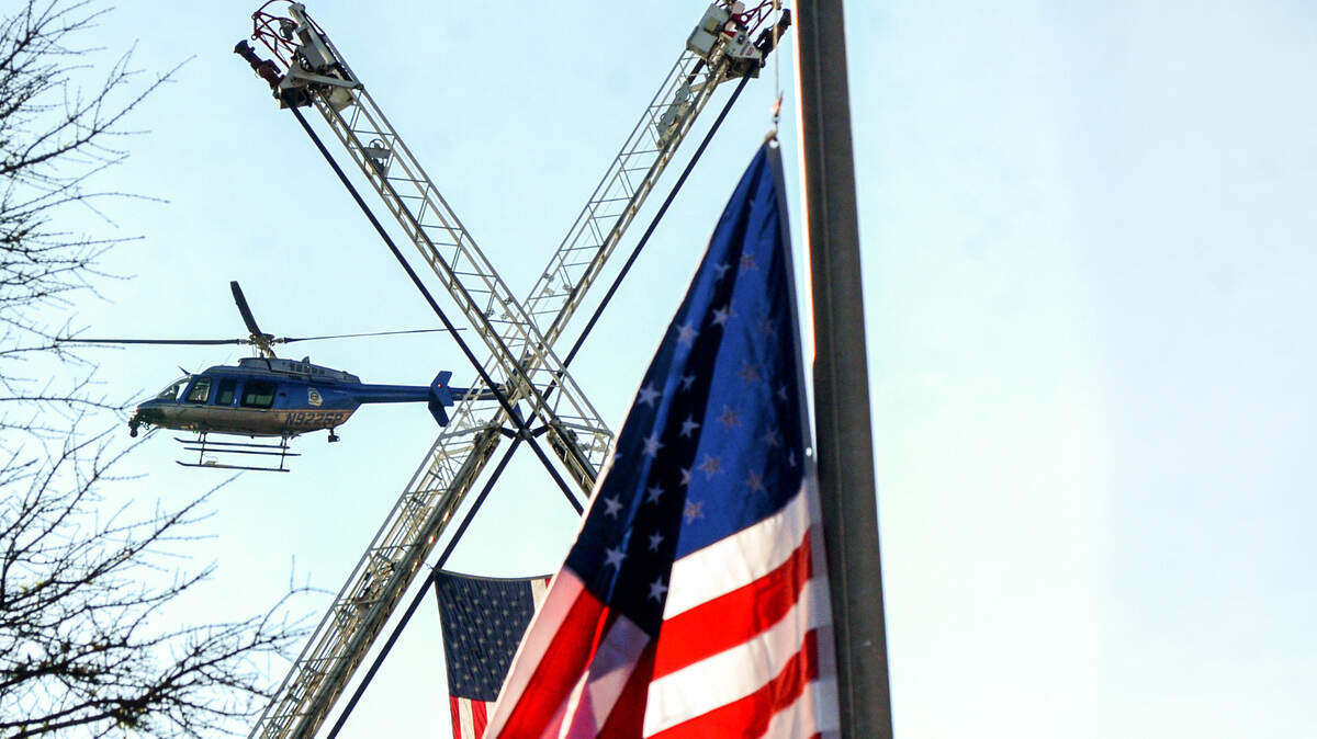 A helicopter flies past a United States flag raised during a 9/11 memorial ceremony in downtown Macon Friday morning. The event was held to “remember the 2001 terrorist attacks and honor the first responders that protect our county and country on a daily basis.”
