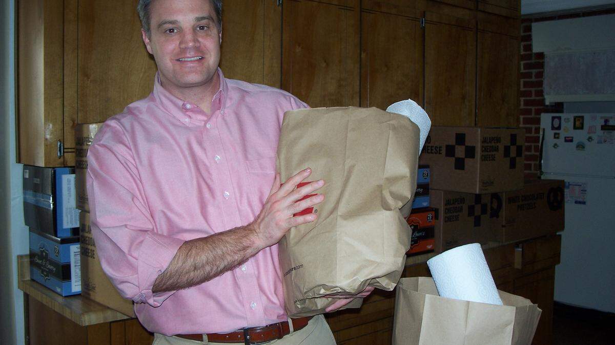 The Rev. Tyler Plaxico, of Byron United Methodist Church, is seen in the congregation's Good Samaritan ministry center with a bag of groceries like those offered to Byron residents in need of food.