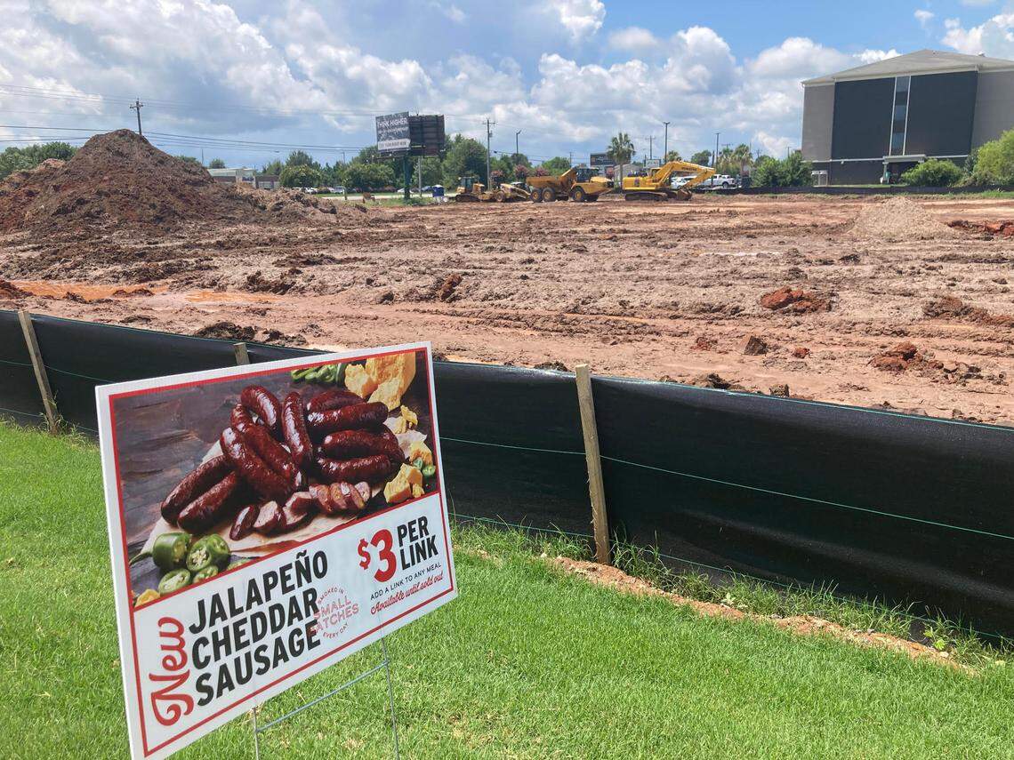 A food sign for Jim ‘N Nick’s Bar-B-Q is staked by the restaurant’s drive-thru near the construction site for a new Texas Roadhouse going up off Watson Boulevard in Warner Robins. Work has been delayed by a series of afternoon and evening showers over the last few days.