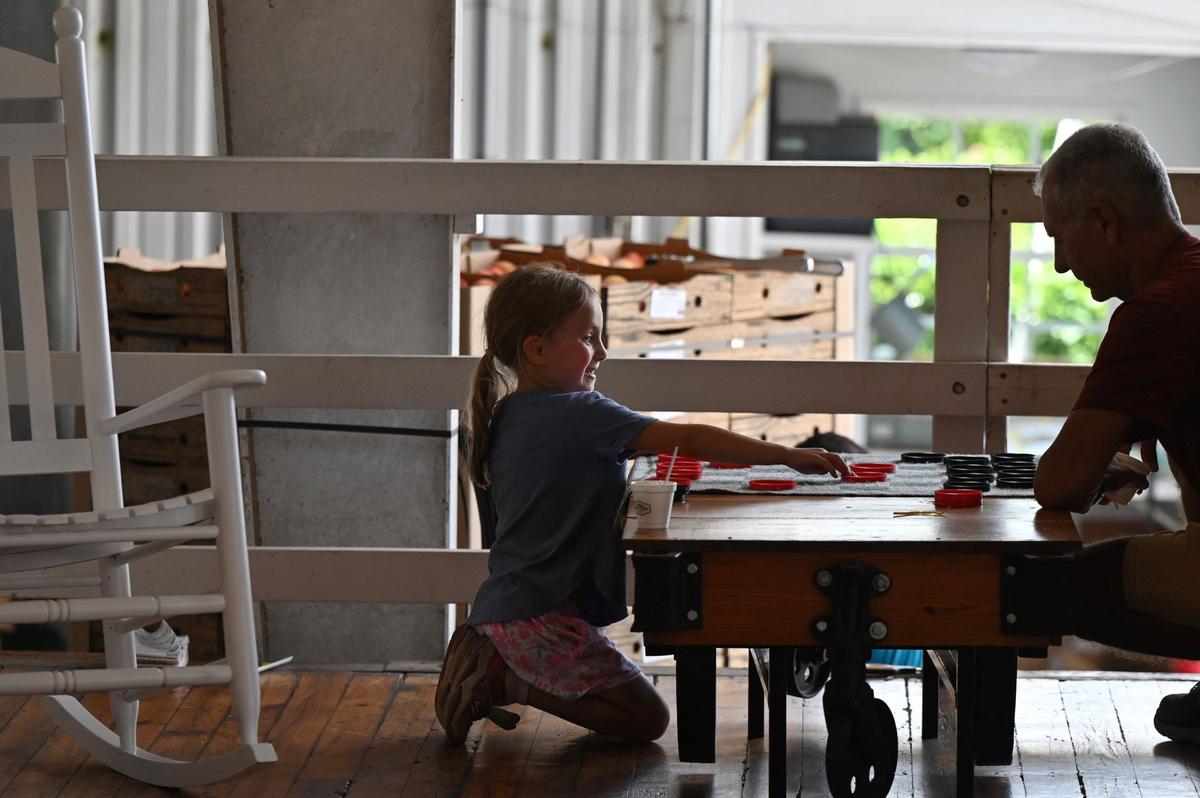 Annie Cordeira (left), 6, plays checkers at Dickey Farms on Wednesday, July 3, 2024, in Musella, Georgia. Dickey Farms is the oldest, continuously operating peach packinghouse in Georgia and offers tours and sells homemade goods and produce in their shop.