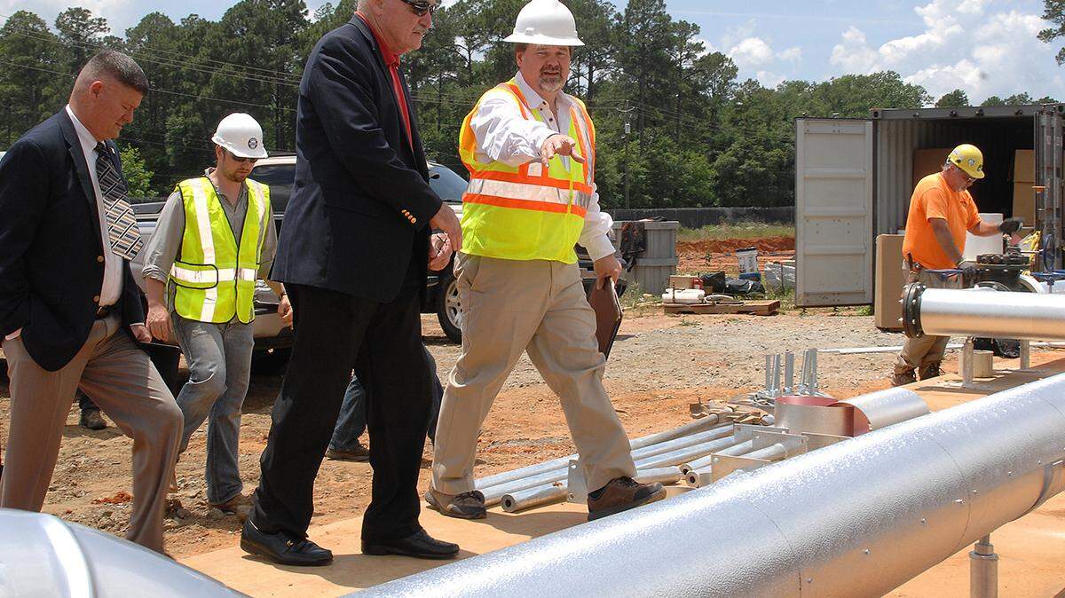 Assistant Secretary of the Navy Dennis V. McGinn (center) tours the ground source heat pump project area during his visit to Marine Corps Logistics Base Albany. The project is a state-of-the-art ground source heat pump system for heating and cooling.