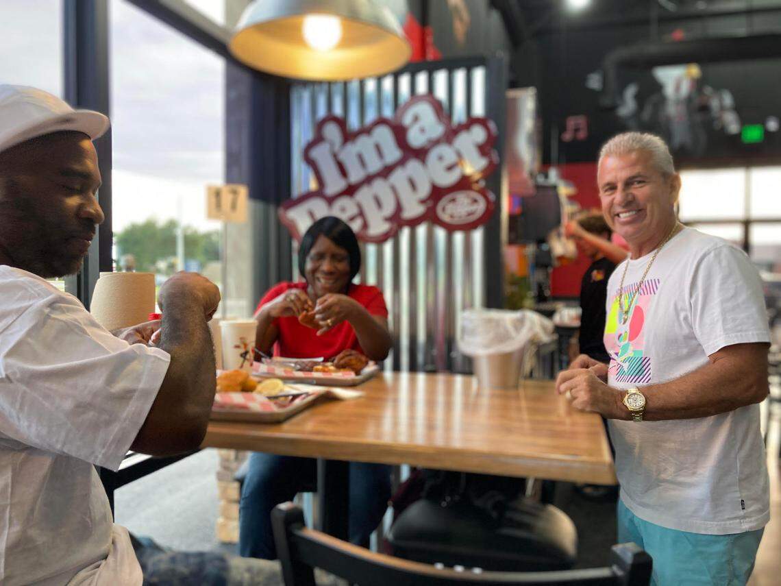 Michael Reece, co-owner of The Hot Chik, (far right) chats with Willie Mae Respress and her son Dwayne at pre-opening event at the new Warner Robins restaurant.