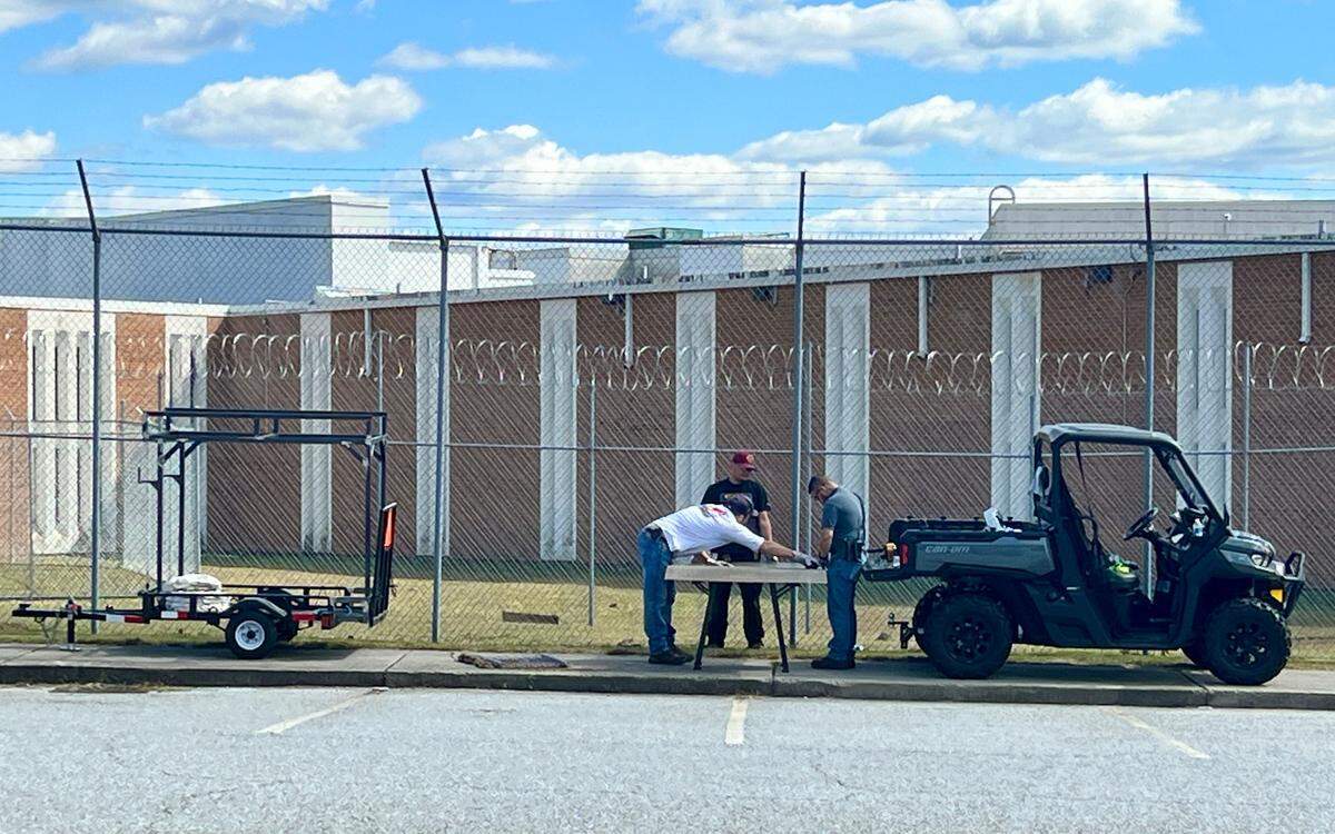 Workers fix a fence at the Bibb County jail in downtown Macon Monday afternoon after four inmates used a hole in the fence to escape early Monday morning.
