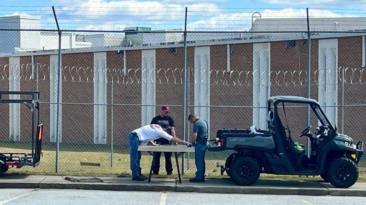 Workers fix a fence at the Bibb County jail in downtown Macon Monday afternoon after four inmates used a hole in the fence to escape early Monday morning.