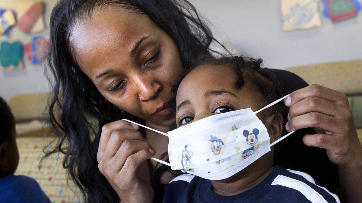 Gwendolyn Tsawo, 41, of Jacksonville, North Carolina, puts a protective face mask on her son, Elijah, 16 months, while sitting in the waiting room at the Duke Children’s Hospital last month in Durham, North Carolina.