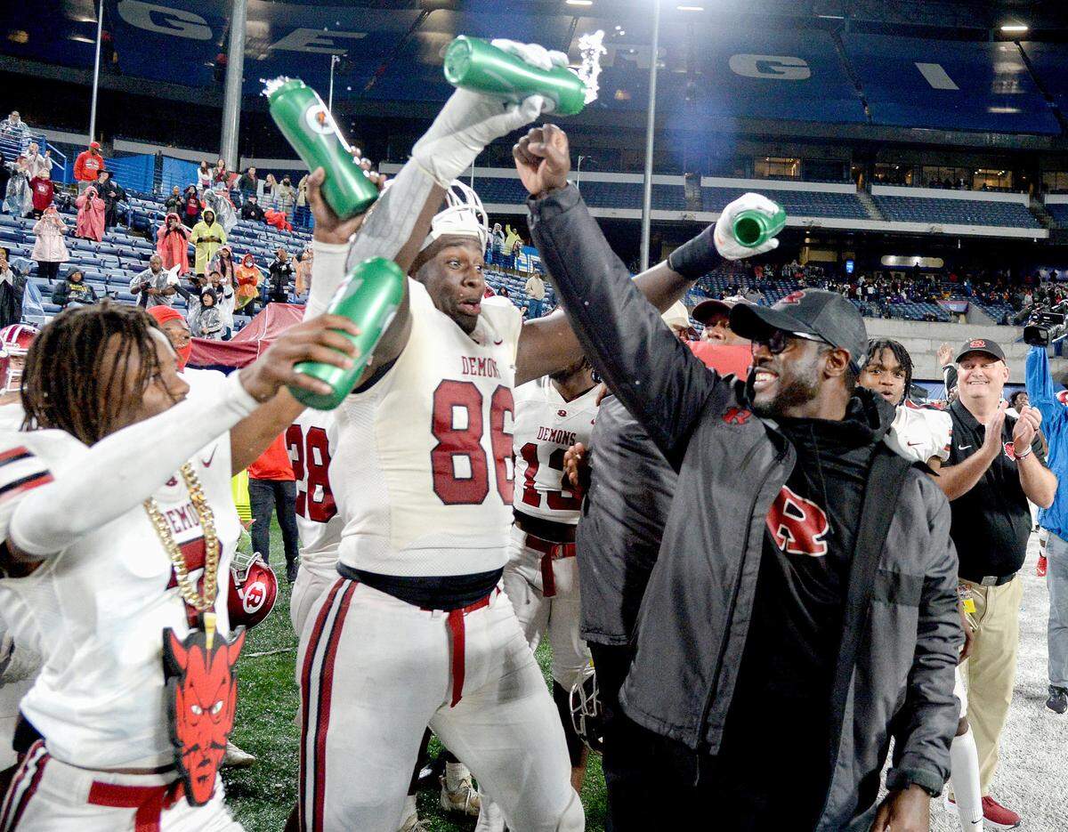 Warner Robins head coach Marquis Westbrook gets water dumped on him by Antwon Jackson (3) and Vic Burley (86) after the Demons’ GHSA 2022 5A State Championship win over Calhoun.