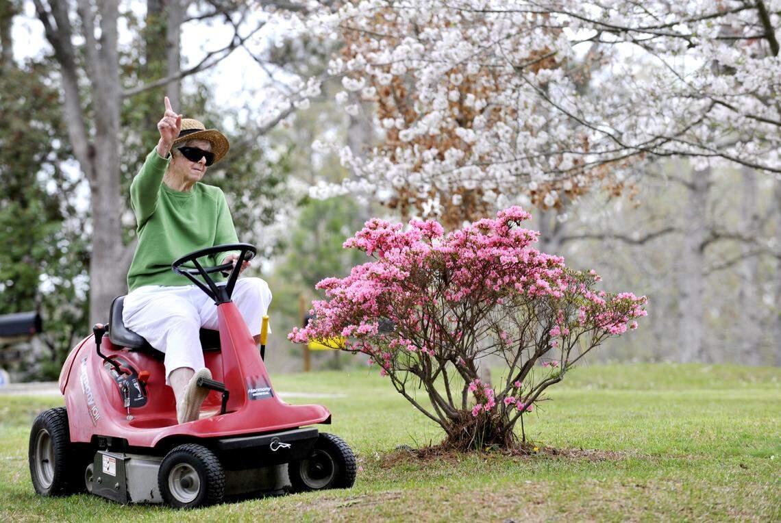 Milred Woods signals one more lap to to go as she mows the grass in her front yard one afternoon in March 2009. She said that her Cherry tree had just gotten to full bloom and that is afraid that the weather the next few days might knock all the blossoms off.