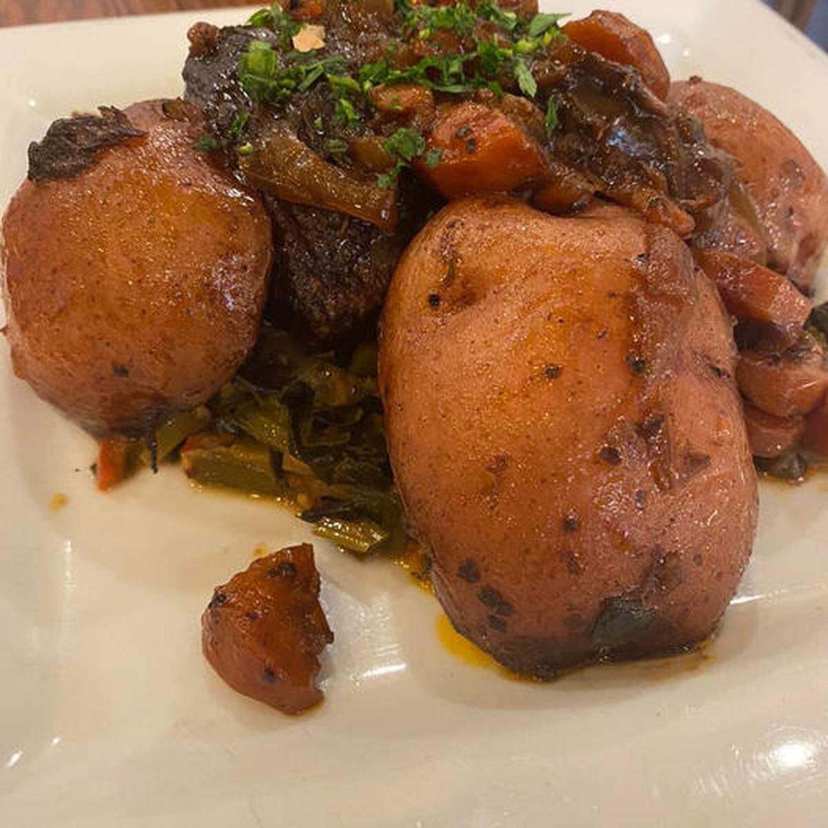 Wagyu pot roast at The Cotton Ranch in downtown Macon. The Wagyu is slow cooked with potatoes in a red wine sauce with herbs and vegetables and served over the restaurant’s signature collard greens.