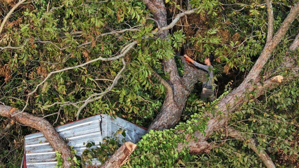 AUGUSTA, GEORGIA - OCTOBER 05: In this aerial view, Joel Chacon uses a chainsaw to cut up a tree that lays on top of a shed as the area recovers from the aftermath of Hurricane Helene on October 05, 2024 in Augusta, Georgia. The Hurricane has left over 200 people dead across Florida, Georgia, North Carolina, South Carolina, and Virginia. (Photo by Joe Raedle/Getty Images)