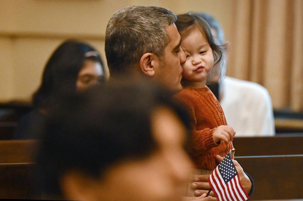 Majid Shakeri, from Athens, Georgia, kisses his daughter Parisa Shakeri, 1, while viewing the naturalization ceremony at the United States District Court Middle District of Georgia on Wednesday, April 9, 2025, in Macon, Georgia. The 22 foreign nationals that petitioned for American citizenship represented 15 countries of origin in the annual ceremony that takes place every spring in Macon.