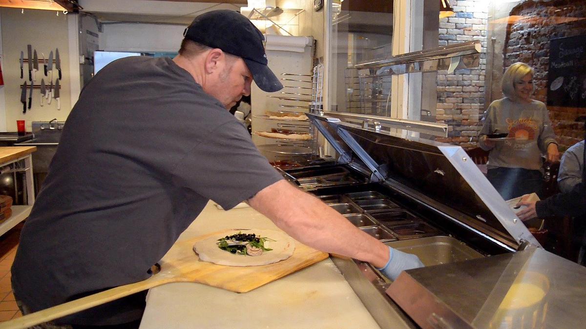 Eric Thomas, owner of Jonah’s on Johnston Pizzeria, makes a calzone while his wife, Laurie, serves customers. “What we want is a local place where people love to come and hang out and eat and can be their weekly place to come with their family,” Laurie says.
