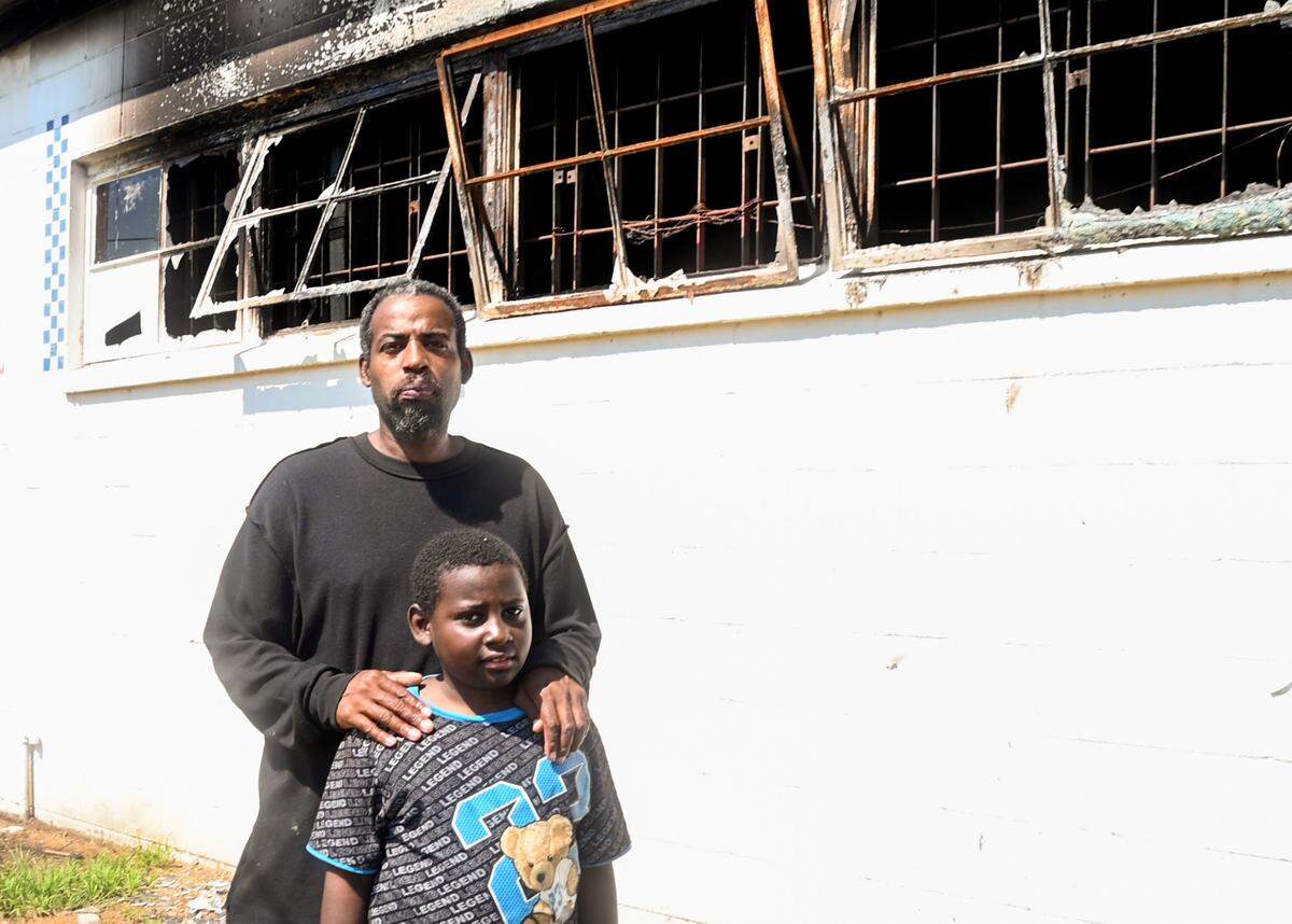Tony Walker, and his son, 8-year-old son, Antonio, outside of what’s left of Doggie Dogs, his walk-up hot dog restaurant that was destroyed by a fire.