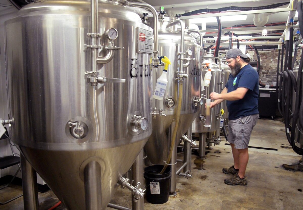 Brian Whitley, co-owner and head brewer at Piedmont Brewery & Kitchen, pours a cylinder of a fall seasonal beer to check the gravity of it. A brewer will check the gravity of a beer before and after the fermenting process to determine how much alcohol the beer has in it.