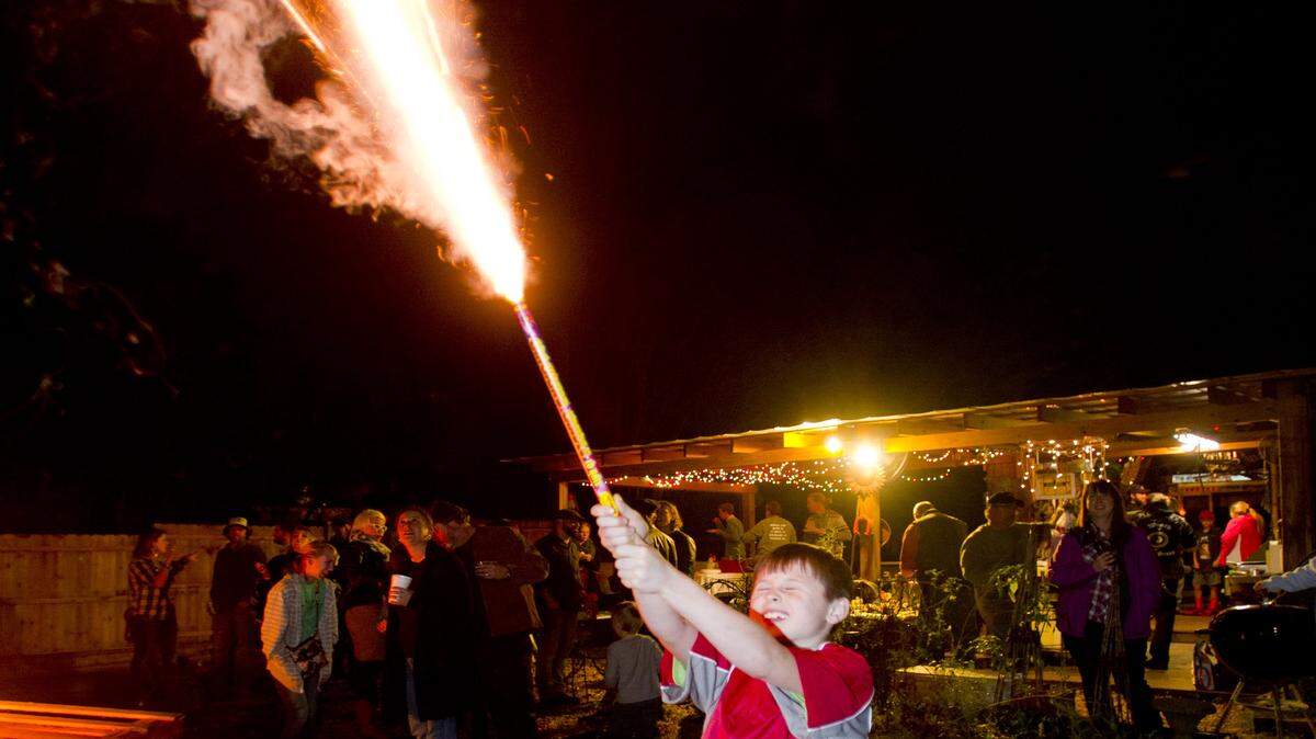 With the supervision of a nearby adult, Brice Whitley holds on tightly and fires a Roman candle into the air before midnight at a New Year's Eve party.