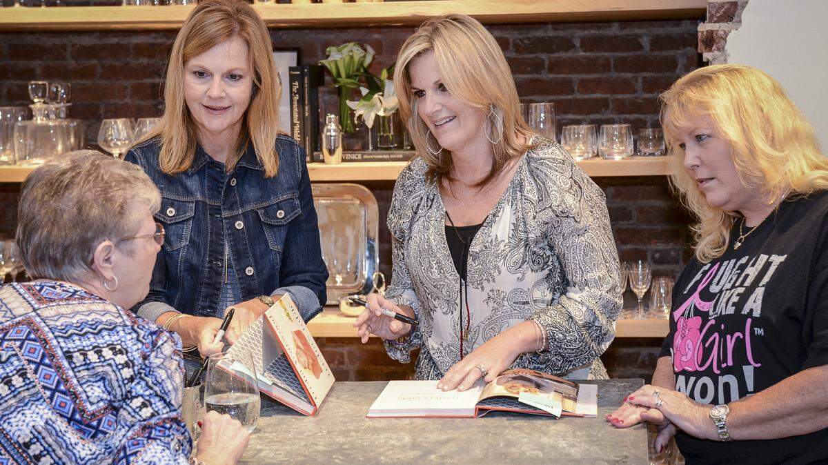 Country music singer Trisha Yearwood, center, and her sister, Beth Yearwood Bernard, second from left, speak with fans seeking autographed copies of Trisha's latest cookbook in August in Atlanta.