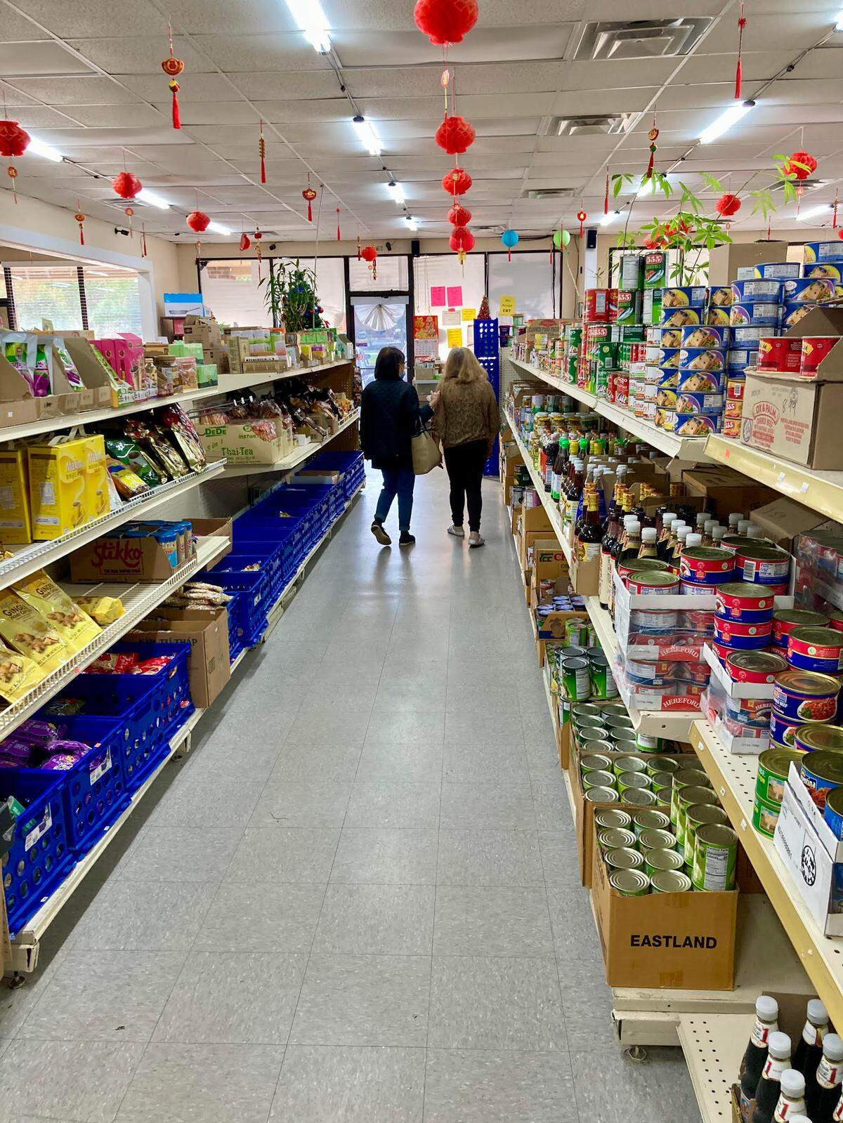 Hermie McMahon, who runs the AB&C Oriental Store in Warner Robins, walks with customer Delores Sher back to the cash register after helping Sher find what she needs in the Asian grocery store.