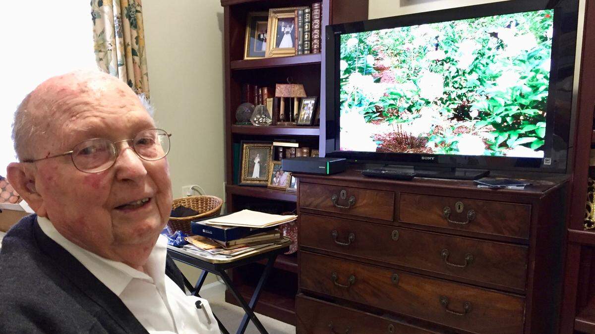 Dr. Rudolph Jones, a retired Macon physician, watches a slide show of his peonies in his home at Carlyle Place.