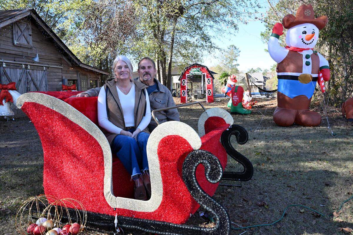 Melissa (left) and her husband Terrell Taylor sit inside a sleigh on their property on Thursday, Dec. 11, 2025, in Fort Valley, Ga. Melissa Taylor began opening her extensive Christmas light display to the public to drive through in 2020. 