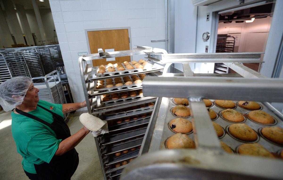 Bakery manager Wanda Gilliand pushes a cart of hot muffins straight from the oven to a place for them to cool.  The central kitchen prepares more than 3,000 muffins dail,y and Timikel Sharpe, executive director of nutrition for the district, said they get a good reception when served.