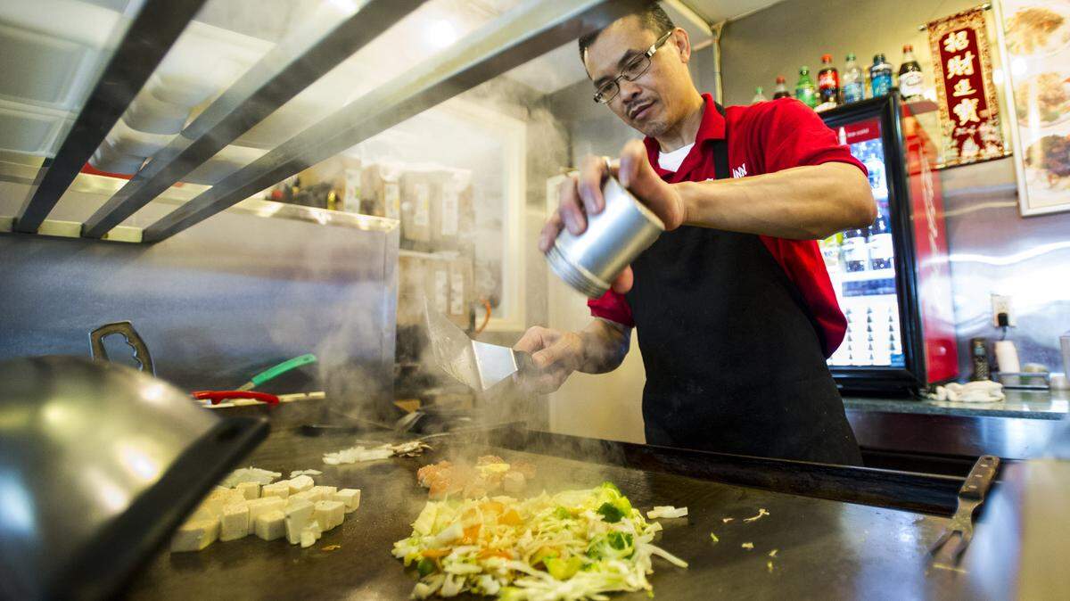 Peter Wu, owner of China Inn, prepares a meal on the grill at his restaurant.