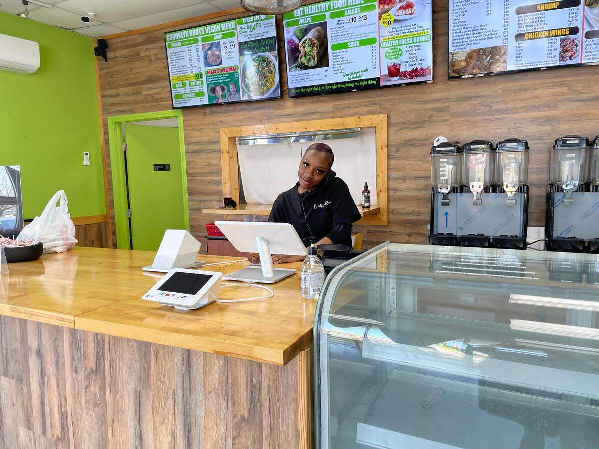 Kayla Middleton smiles from behind the counter at Crooklyn Roots, a new geared-for-takeout restaurant offering authentic Jamaican and vegan dishes in Byron.