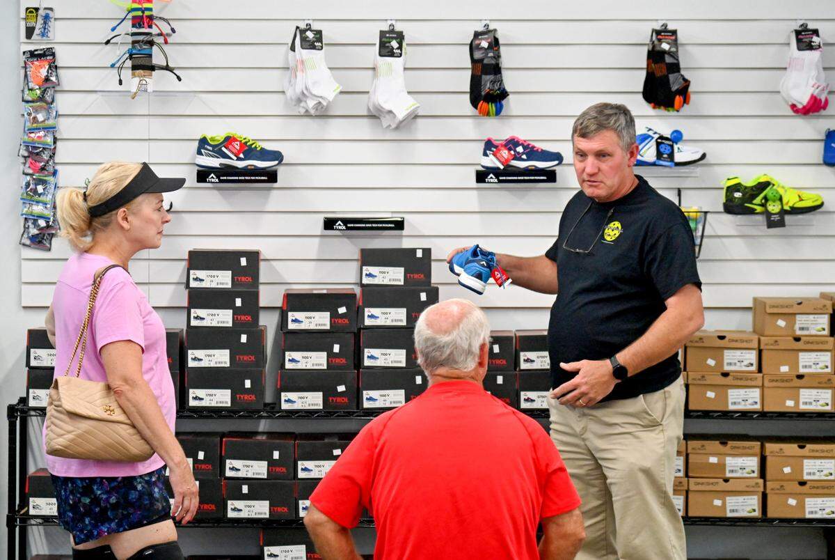 Owner Greg Stokes helps customers choose a pair of shoes available at Pickleball Sports at 4446 Forsyth Road In Macon.