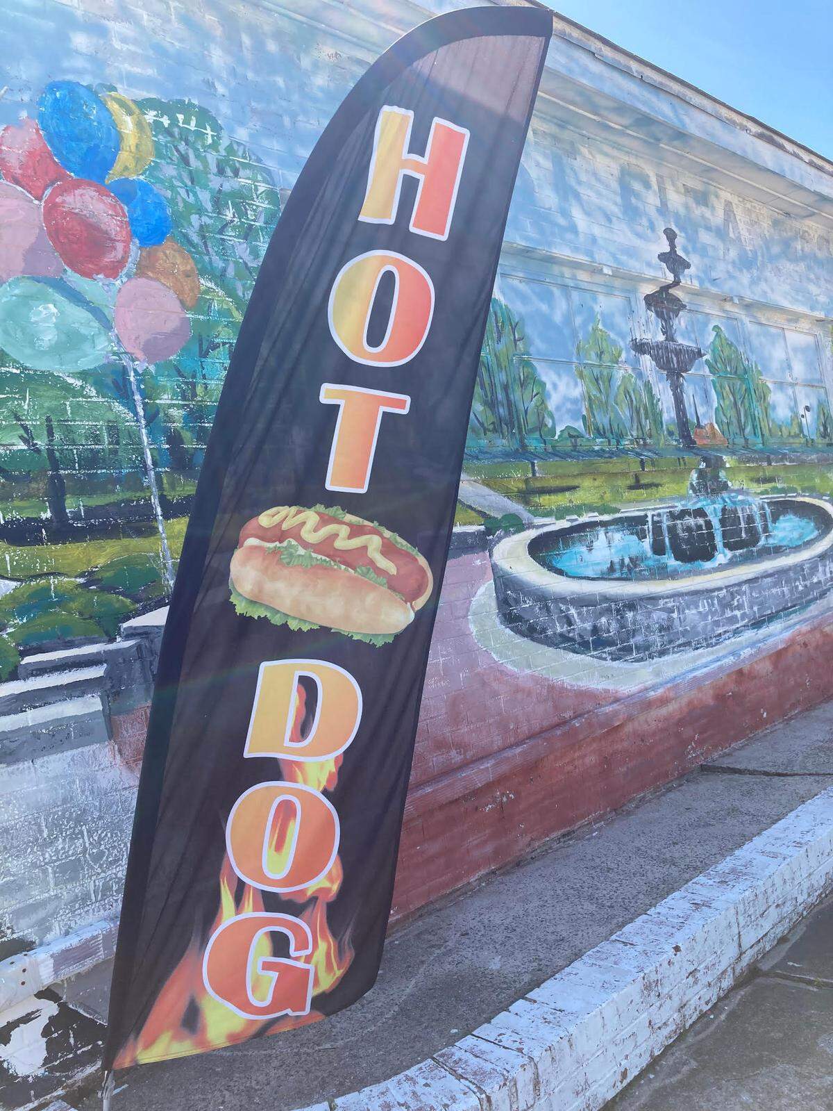 Driving north on Pio Nono Avenue, Doggie Dogs is easy to miss except for a vertical hot dog banner. That’s because the side of the building that parallels Pio Nono Avenue has a water fountain mural. The hot dog spot is on the side of the business that’s painted like a red and white dog house.
