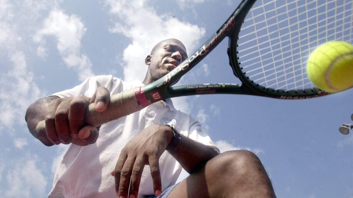 062801 Photo by Nick Oza Tennis Coach Carl Hodge shows a jumping exerciseto the youth at Tatnall Square Park. Carl Hodge, a city tennis Pro holding a tennis camp in the inner city for kids who can’t afford tennis lesson.