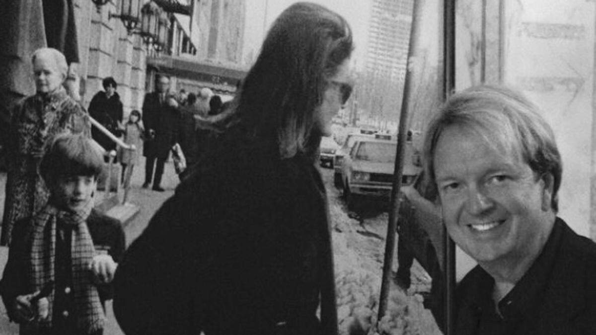 Photo of Mark Ballard taken in front of a photo of Jackie Kennedy and "John John" in New York.