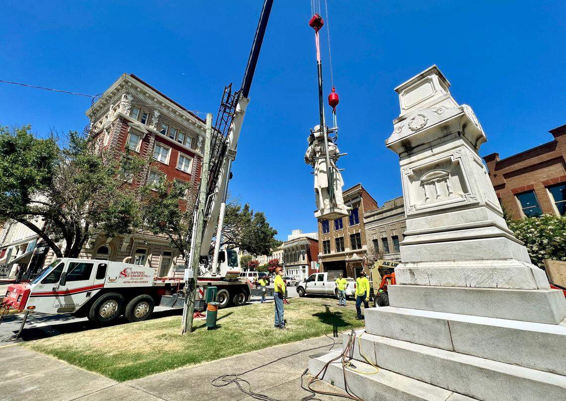 Crews lower the Confederate monument on Cotton Avenue while removing it Wednesday morning. The monument will be relocated to Whittle Park in from of Rose Hill Cemetery.