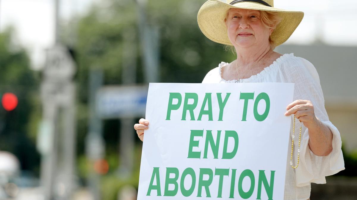 Gina Lucas holds a sign in front of 833 Walnut St. in Macon.