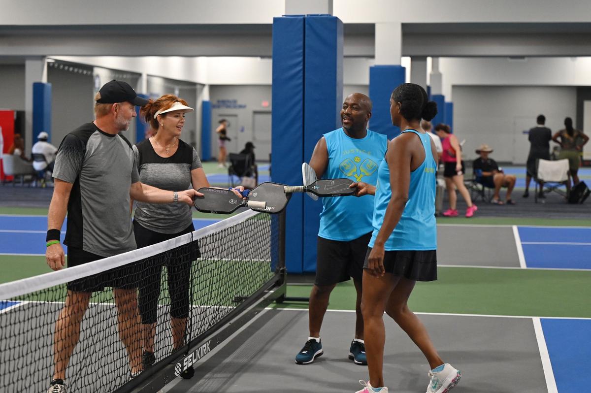 From left to right: Richard King, Collette King, Tracy Rucker and Edana Davis tap paddles after their mixed doubles match on the second day of the United States Senior Pickleball Indoor National Championships on Saturday, July 13, 2024, at Rhythm and Rally Sports & Events in Macon, Georgia. United States Senior Pickleball hosted its inaugural indoor national championships this year, spanning three days and bringing hundreds of seniors to compete in Macon from across the country.