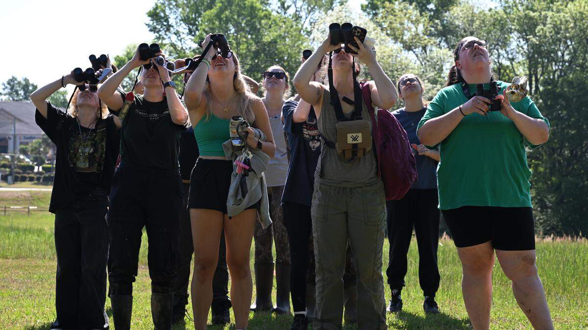 Professor Michelle Moyer and Georgia College and State University students use their binoculars to look at an orchard oriole while conducting field research at Andalusia Farm on Friday, April 17, 2026, in Milledgeville, Ga.