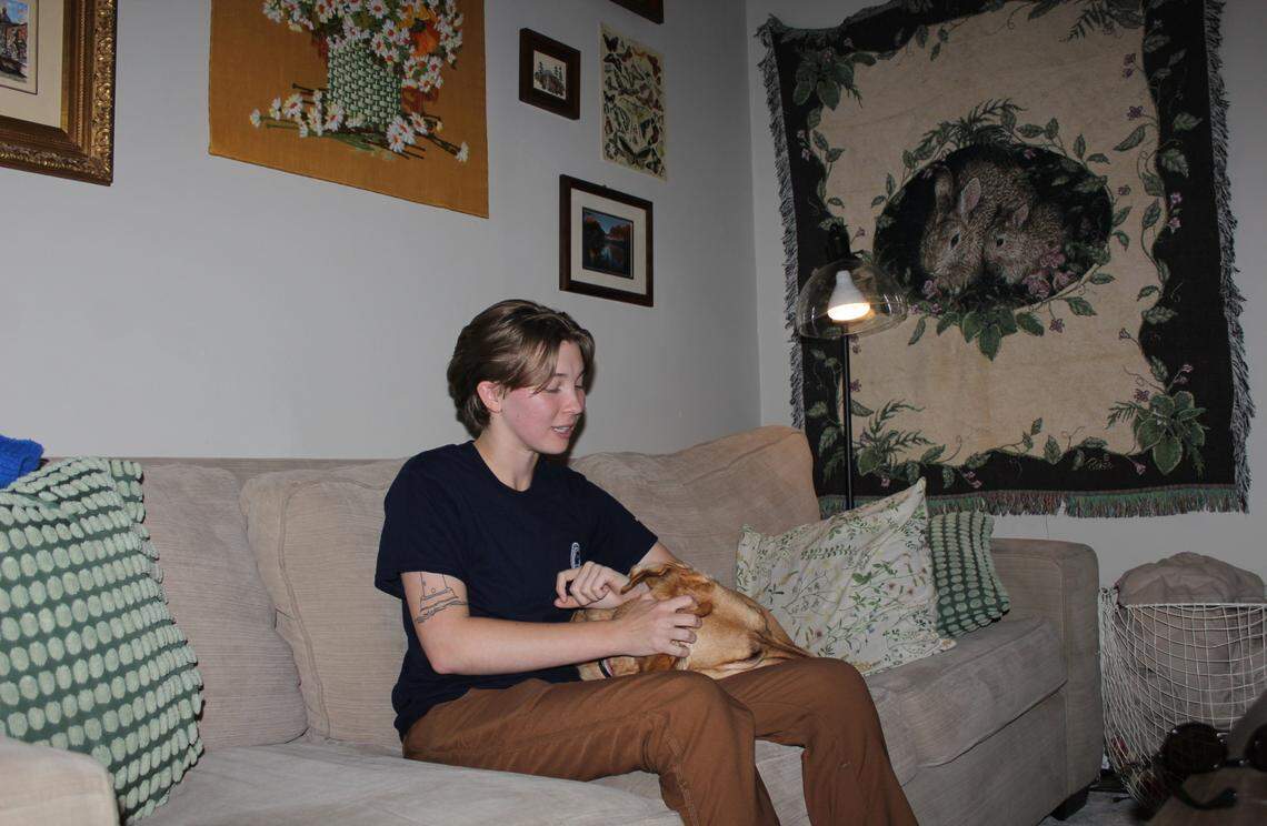 Ryleigh Palmer, 23, and their service dog Chloe chill on their living room couch on Monday, Nov. 11, 2024, in Milledgeville, Ga.