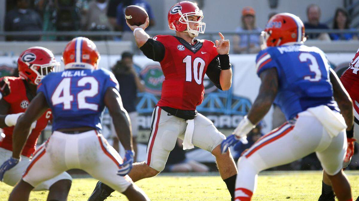 Georgia quarterback Faton Bauta (10) throws a pass as he is pressured by Florida defensive back Keanu Neal (42) and linebacker Antonio Morrison (3) during the first half of an NCAA college football game Saturday, Oct. 31, 2015, in Jacksonville, Fla.