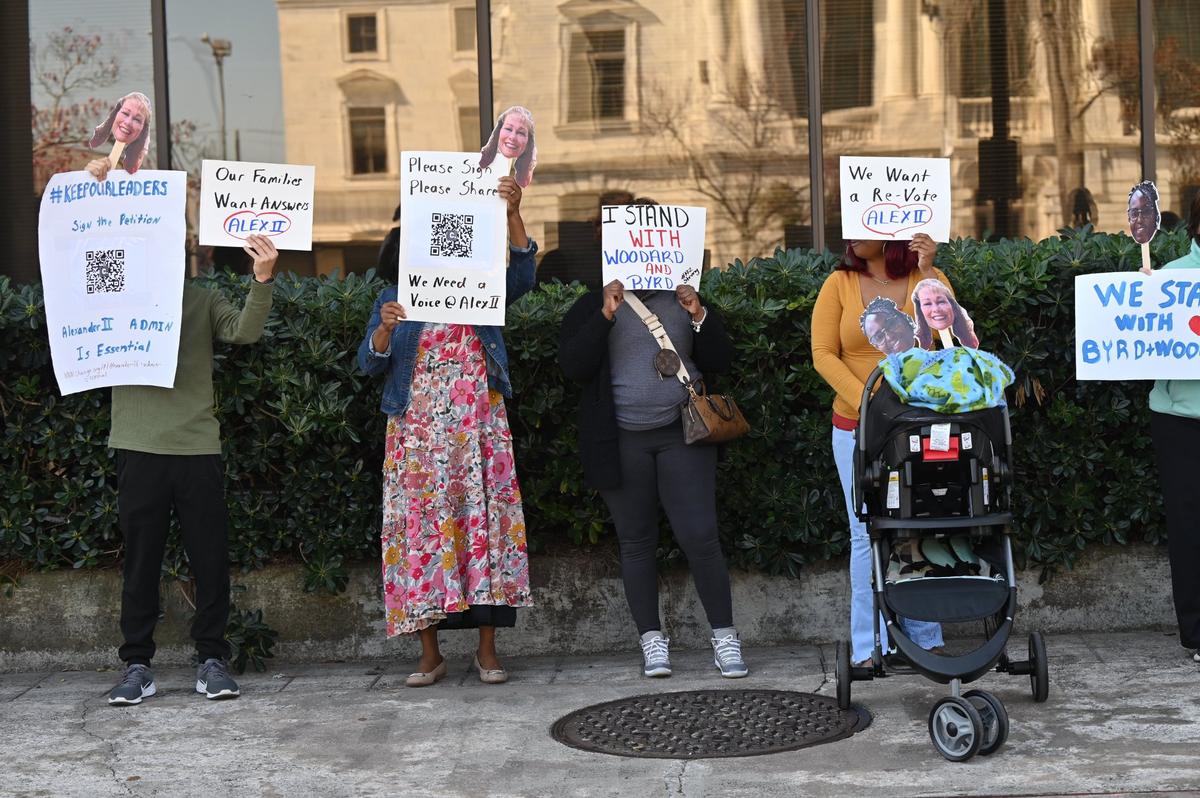 Community members hold signs with a QR code for a petition in support for Alexander II Elementary School administration, as well as popsicle sticks with the faces of Principal Angel Woodard and assistant principal Dr. Meredith Byrd during a protest against the principals’ unexpected termination on Friday, March 7, 2025, in front of the Bibb County Board of Education in downtown Macon, Georgia. A small but vocal group of parents and community members protested on Friday afternoon calling for the Bibb County school district to give answers as to why the Alexander II Elementary Schools principals’ contracts were not extended.