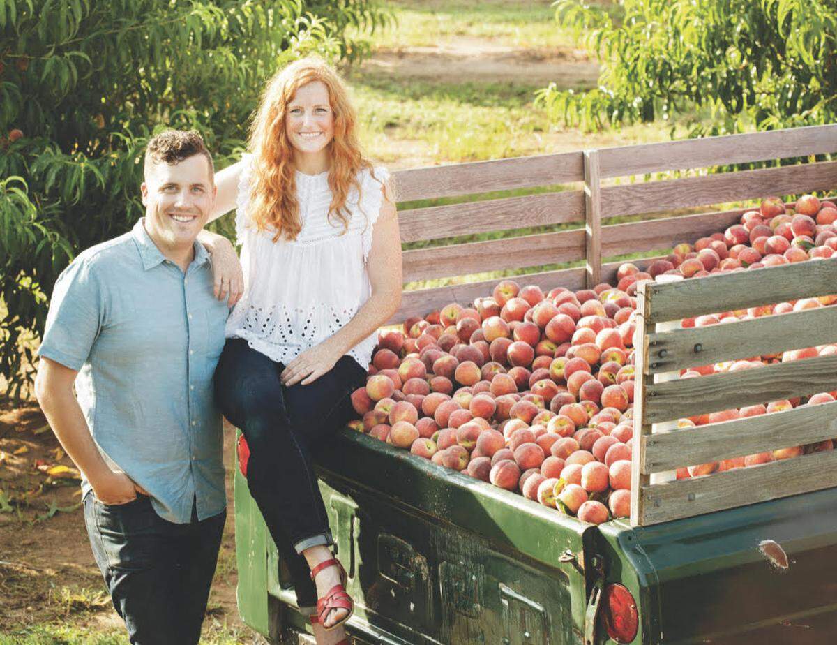 Stephen and Jessica Rose stand at their 1964 Jeep Gladiator that they sold peaches out of when they started their business The Peach Truck in 2012. They now travel around the country, selling two tractor trailer loads of Middle Georgia peaches a day directly to customers.