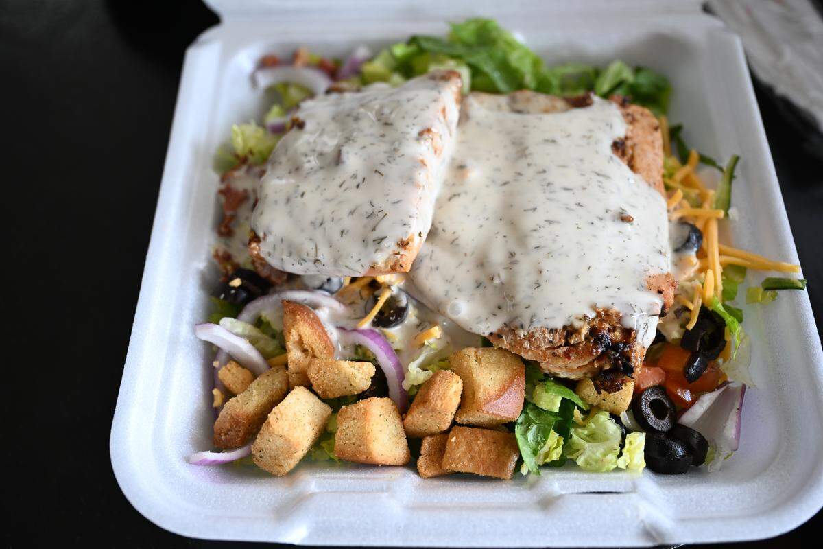 The salmon salad from The Salad Palace features two salmon fillets, romaine lettuce, tomatoes, cucumbers, red onions, eggs, cheese, black olives, red and yellow peppers, bacon bits, croutons and choice of dressing.