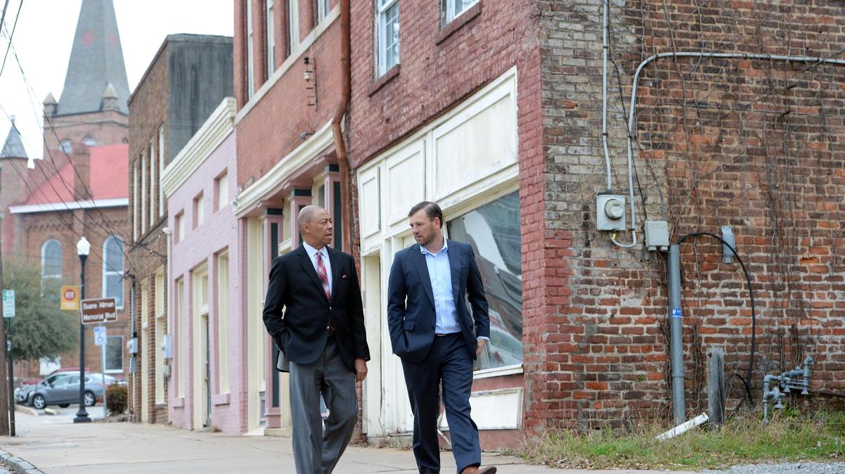 Virgil Adams and Brian Adams, right, walk along Forsyth Street, formerly Cotton Avenue, where the two Macon lawyers have purchased an entire block of historic properties they are now restoring.