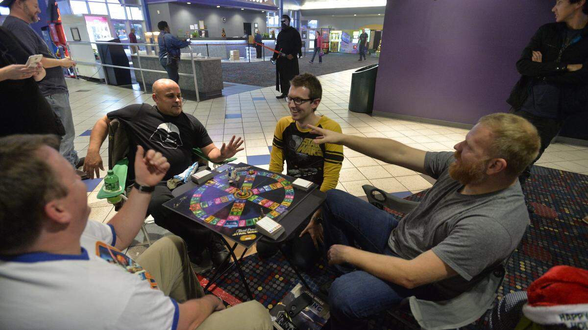 From left, admitted "Star Wars" geeks James Freeman, Allan Boggs, Eric Robbins and Michael Carson play a game of "Star Wars" Trivial Pursuit in the lobby of the AmStar 16 movie theater in Macon as they wait for the latest offering of their favorite film franchise to premiere.