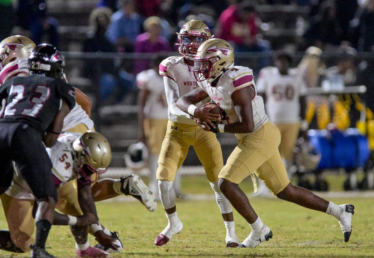 Westside quarterback hands off the ball to running back Kadiphius Iverson in action Thursday night against Howard High.