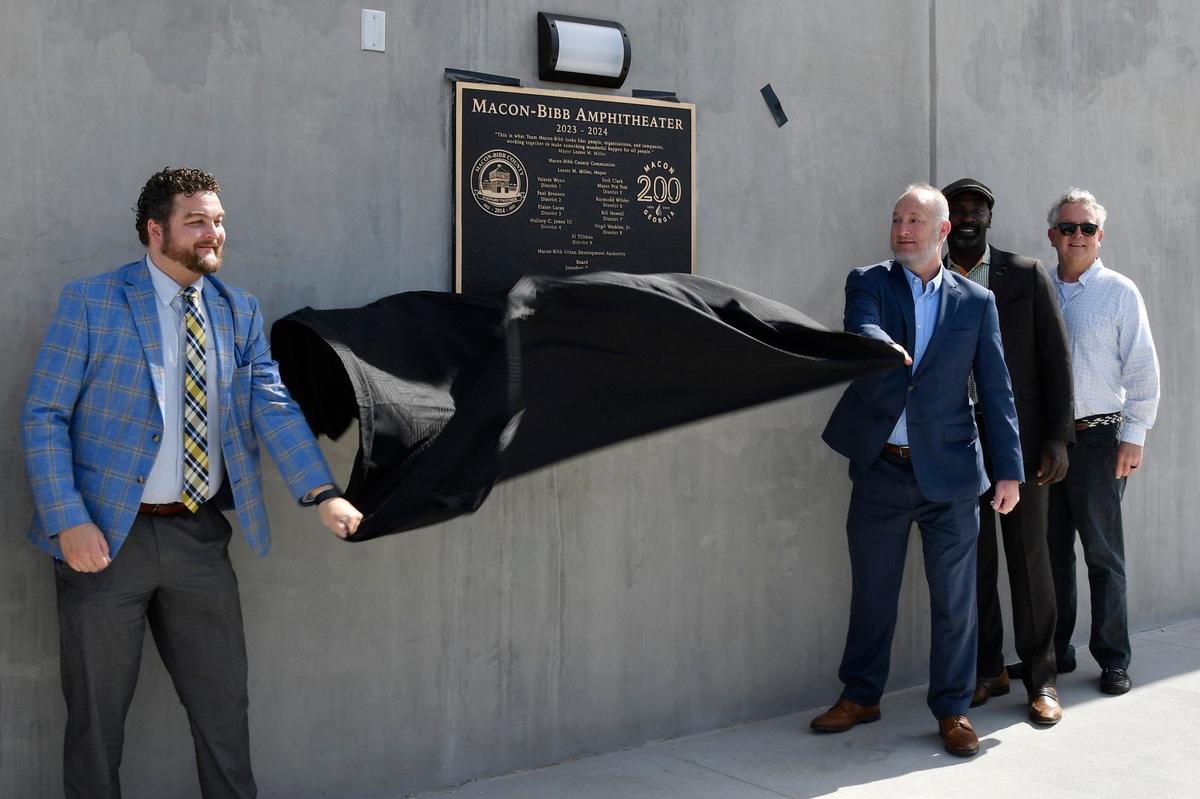 Macon Urban Development Authority executive director Alex Morrison (left) and Macon-Bibb County mayor Lester Miller pull off the tarp over the new plaque outside of the Atrium Health Amphitheater on Friday, May 31, 2024, in Macon, Georgia. The 12,000 seat Atrium Health Amphitheater opened in March and will host a number of events in the upcoming months.