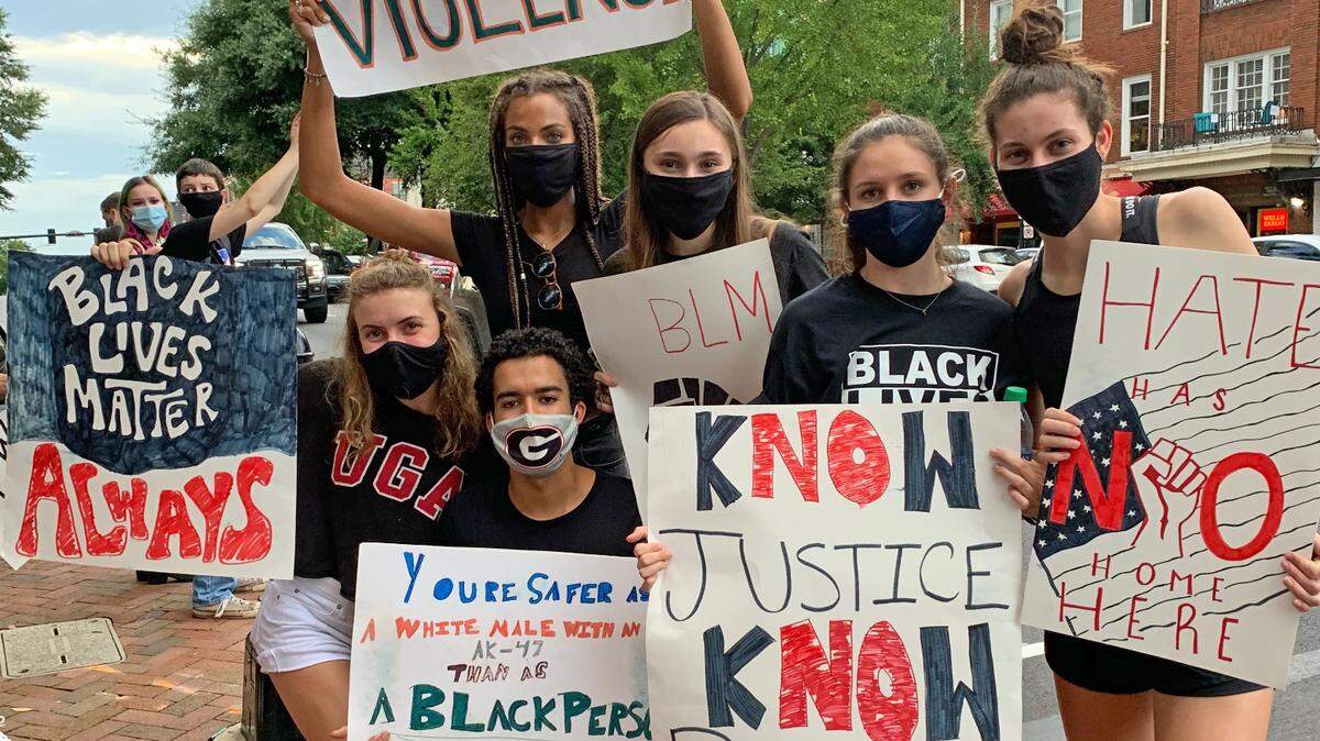 A group of Georgia athletes, including cross country runners Dru Milton and Kayla Smith, hold signs while protesting in downtown Athens. 